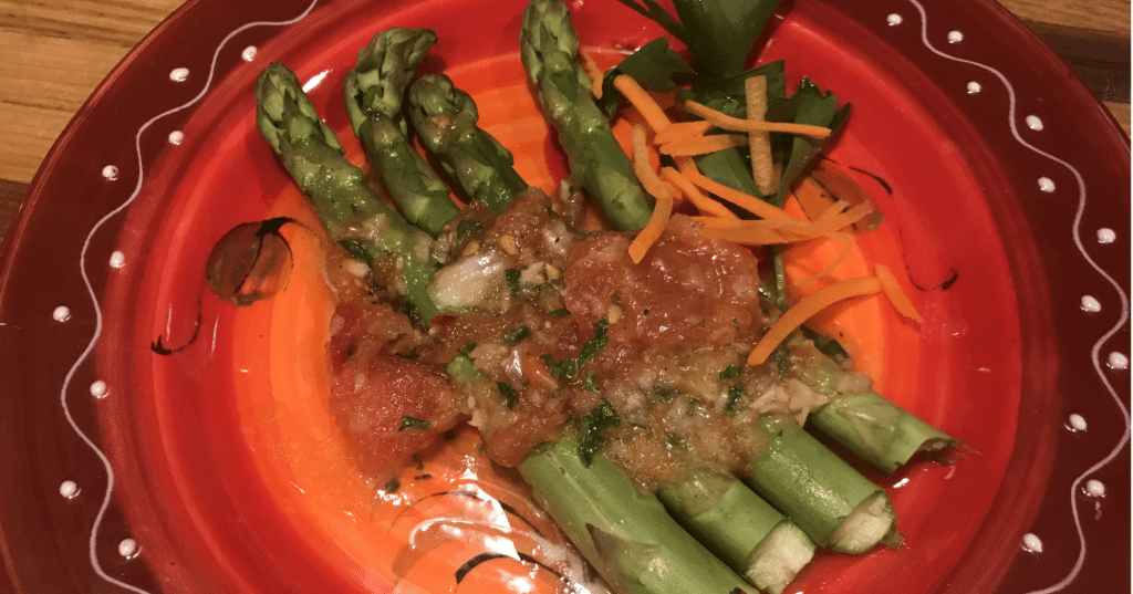 Tomato onion dressing on top of fresh asparagus with carrots